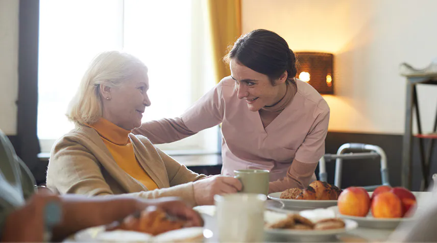 Staff member serving resident her breakfast.