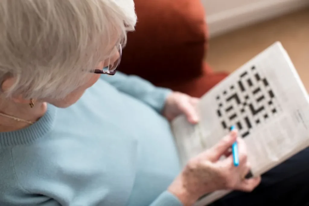 A senior woman doing a crossword puzzle in the newspaper.