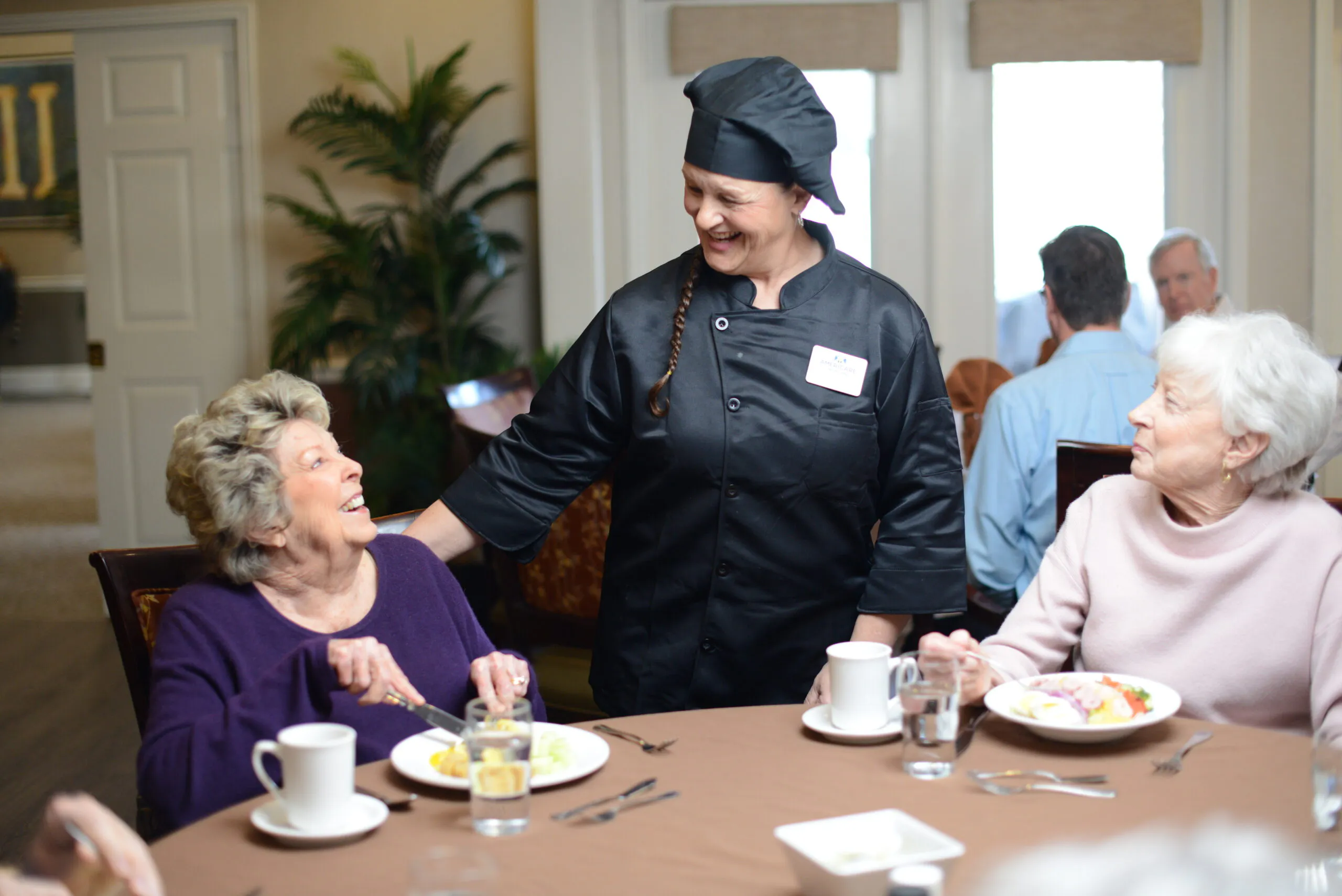 chef smiling at residents having coffee