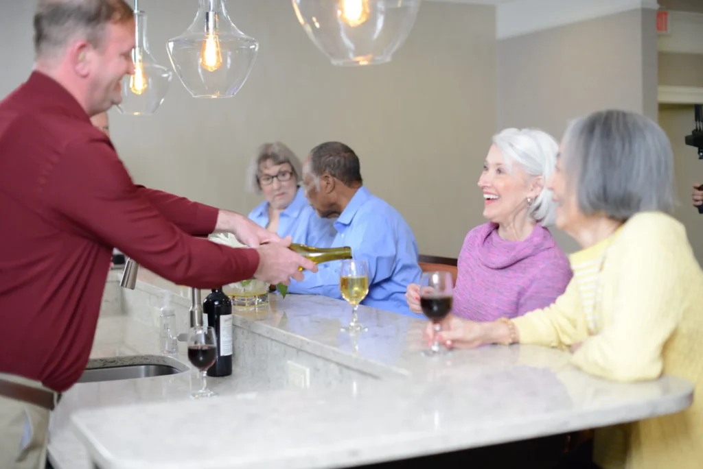 man pouring wine for smiling residents